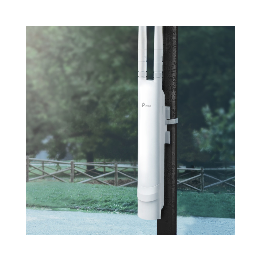 White outdoor wireless router on a pole with a blurred green landscape in the background