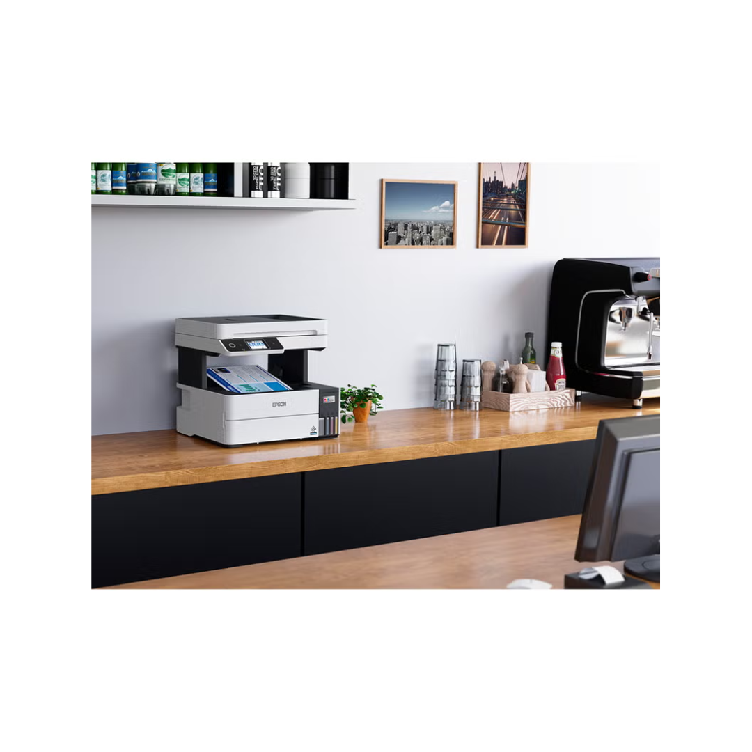 Office desk with printer, coffee machine, and office supplies against a white wall.