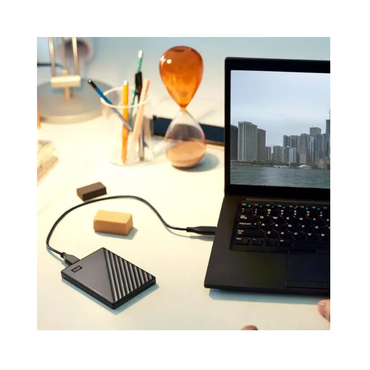 External hard drive connected to a laptop on a desk with office items.