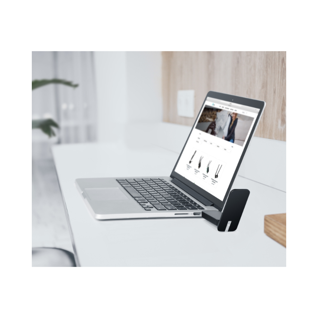 Laptop on a desk with a phone on its stand displaying an e-commerce website.