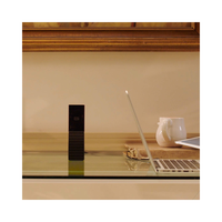 Laptop and other items on a wooden desk with a beige wall in the background