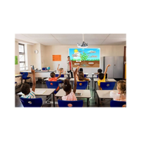 Classroom with children raising hands, facing a screen displaying educational content.